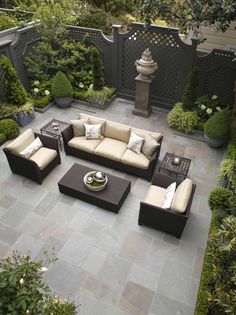 an outdoor living area with couches, tables and potted plants on the ground