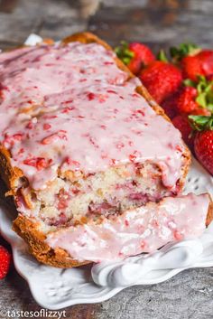 strawberry bread with icing on a plate next to strawberries