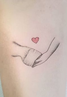 a woman's hand holding a heart tattoo on her left side ribcage