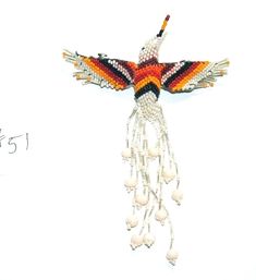 a colorful beaded bird hanging on a white wall