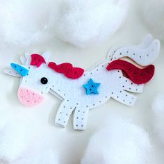 a felt unicorn with red, white and blue stars on it's head sitting in the clouds