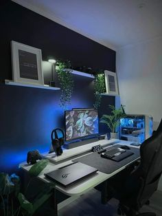 a computer desk with two monitors and a laptop on it in front of a plant