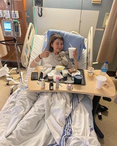 a woman sitting in a hospital bed with food and drinks