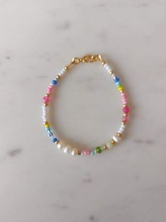 the multicolored beaded bracelet is shown on a marble surface