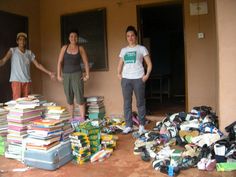 three people standing in front of a pile of books on the ground next to a building