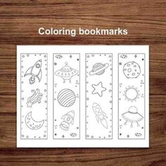 coloring bookmarks for kids with space and stars on the pages, sitting on a wooden surface