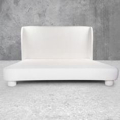 a white couch sitting on top of a cement floor next to a gray concrete wall