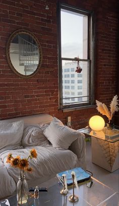 a living room filled with furniture and a large window next to a brick wall covered in windows