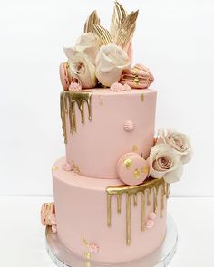 a pink cake with gold drips and flowers on top