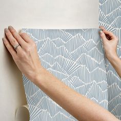 two hands are holding onto a blue and white wallpaper