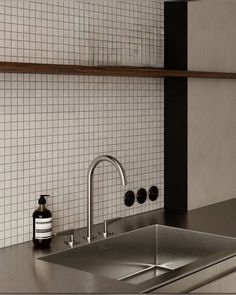 a stainless steel kitchen sink and faucet with soap dispenser next to it