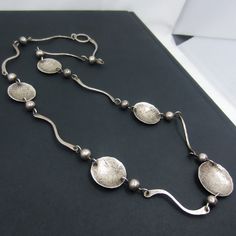 This fab Modernist necklace circa 1960's is most likely a studio piece and has hand worked and hammered alternating disc and squiggle links.  Very striking on and beautifully made! Measures 26" length.  Largest disc measures 1" diameter. Stamped 'STERLING' and tested.   Weighs 29 grams. In excellent vintage condition! All purchases from Bavier Brook arrive in an elegant box, fully wrapped in fine paper. Please inquire for international shipping. Don't hesitate to ask if you have any questions, w Modern Silver Hammered Necklace, Luxury Modernist Sterling Silver Jewelry, Modernist Silver Jewelry With Polished Finish, Luxury Handmade Modernist Necklace, Cold Connections, Luxury Modernist Sterling Silver Necklace, Modernist Polished Silver Necklaces, Hudson Ny, Modernist Jewelry