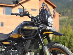 a black and yellow motorcycle parked in front of a building with mountains in the background