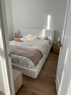 a white bed sitting in the middle of a bedroom next to a wooden flooring