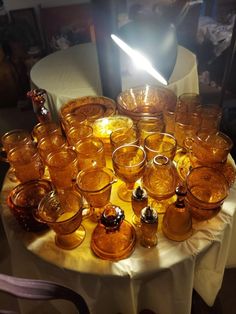 a table topped with lots of glasses on top of a white cloth covered round table