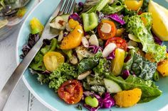 a blue plate topped with a salad next to a fork