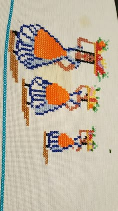 a cross - stitch pattern on a white cloth with blue trimmings and an image of two people holding hands