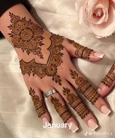 a woman's hand with henna on it and a rose in the background