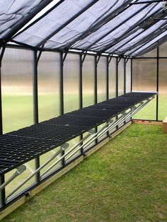 the inside of a greenhouse with several rows of benches in front of it and grass on the ground