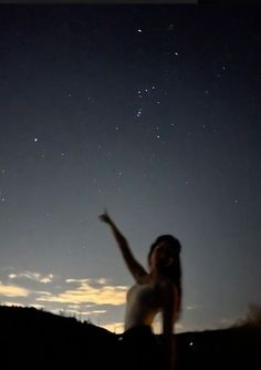 a woman reaching up into the sky at night