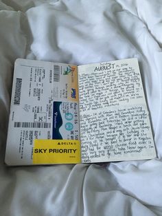 an airplane ticket sitting on top of a white sheet covered bed next to a pillow