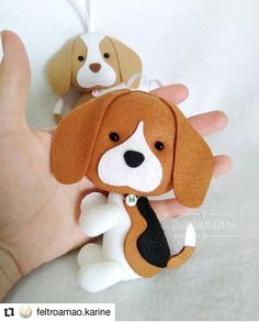 a hand is holding two stuffed dogs on it's fingers, one has a black tie and the other has a brown and white beagle