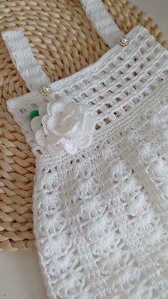 a white crocheted bag sitting on top of a woven basket