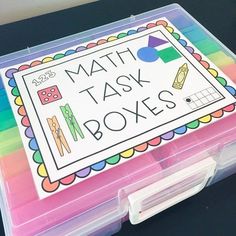 a colorful box with some writing on it and two plastic containers filled with colored pencils