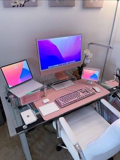 a desk with two laptops and a desktop computer on it, in front of a white chair