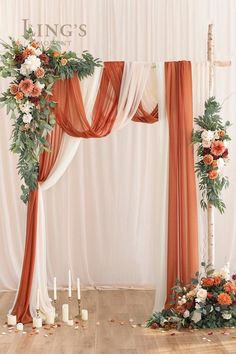 an orange and white wedding arch decorated with flowers, greenery and candles on the floor