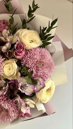 a bouquet of pink and white flowers sitting on top of a piece of wrapping paper