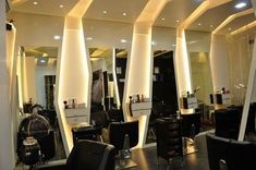 the interior of a hair salon with chairs and mirrors in front of it, all lit up