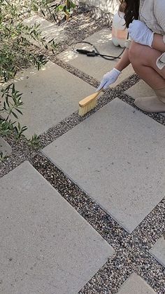 a woman kneeling down on the ground with a brush in her hand and scrubbing it