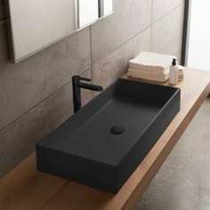 a bathroom with a wooden counter top and black square shaped sink in front of a mirror