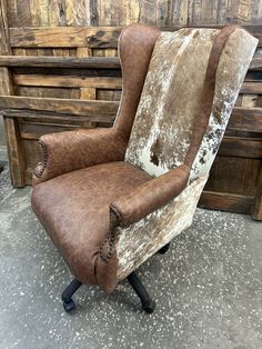 a brown and white chair sitting on top of a floor next to a wooden wall