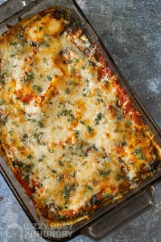 a casserole dish with cheese and spinach in it on a gray surface