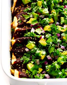 a white casserole dish filled with meat, vegetables and sesame seed sauces