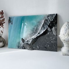 a black and white painting sitting on top of a table next to a vase filled with flowers