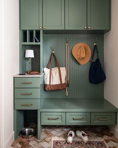 a green bench with two coats hanging from it's back and shoes on the floor