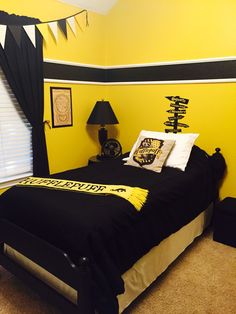 a bedroom decorated in black and yellow with decorations on the wall, bedding and curtains