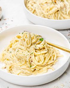 two white bowls filled with pasta and garnished with parmesan sprinkles