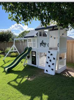 there is a play house with a slide in the back yard, and a tree on the other side