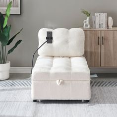 a white chair sitting on top of a rug next to a wooden cabinet and potted plant