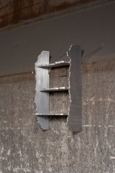 a metal shelf on the side of a concrete wall with peeling paint and chipping