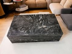 a black marble box sitting on top of a white rug in front of a couch