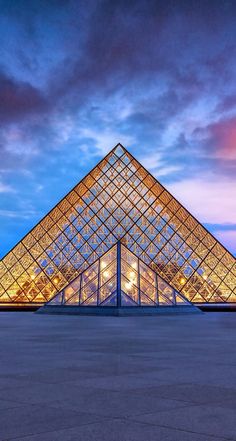 the pyramid is lit up at night in front of a blue sky with white clouds