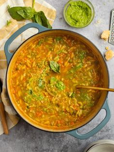 a large pot filled with soup next to some spoons and other food on the table