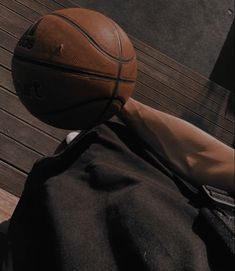 a basketball sitting on top of a wooden floor next to a person's leg