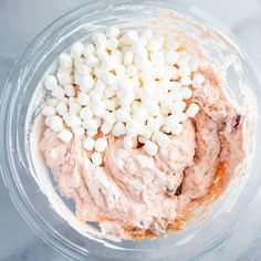 a bowl filled with marshmallows on top of a marble counter next to a knife