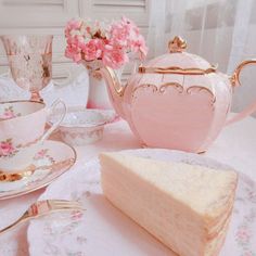 a piece of cake sitting on top of a white plate next to a pink tea pot